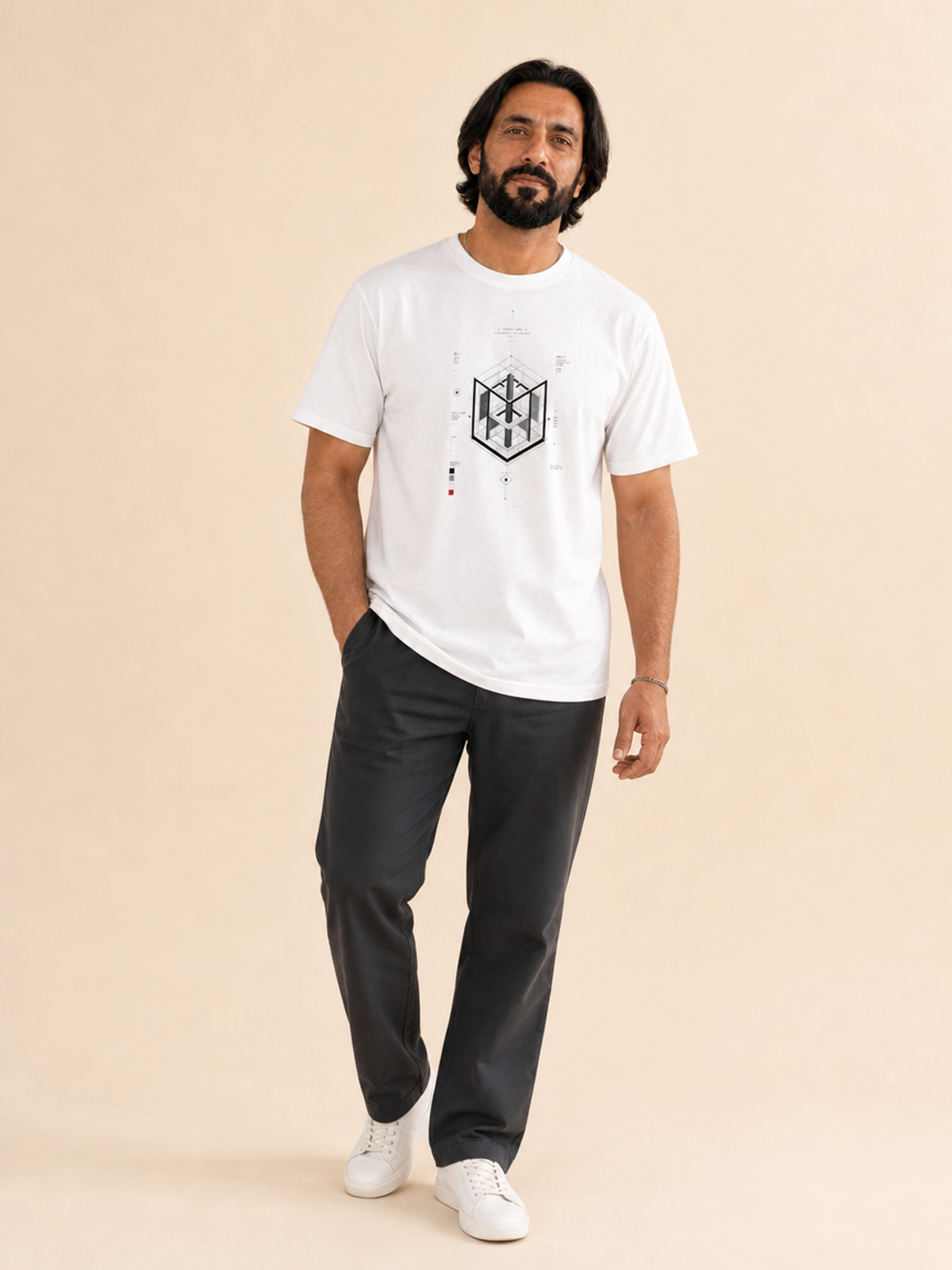 A male model wearing a white crew neck t-shirt featuring a centered black-and-grey geometric architectural blueprint graphic, paired with white trousers against a neutral background.