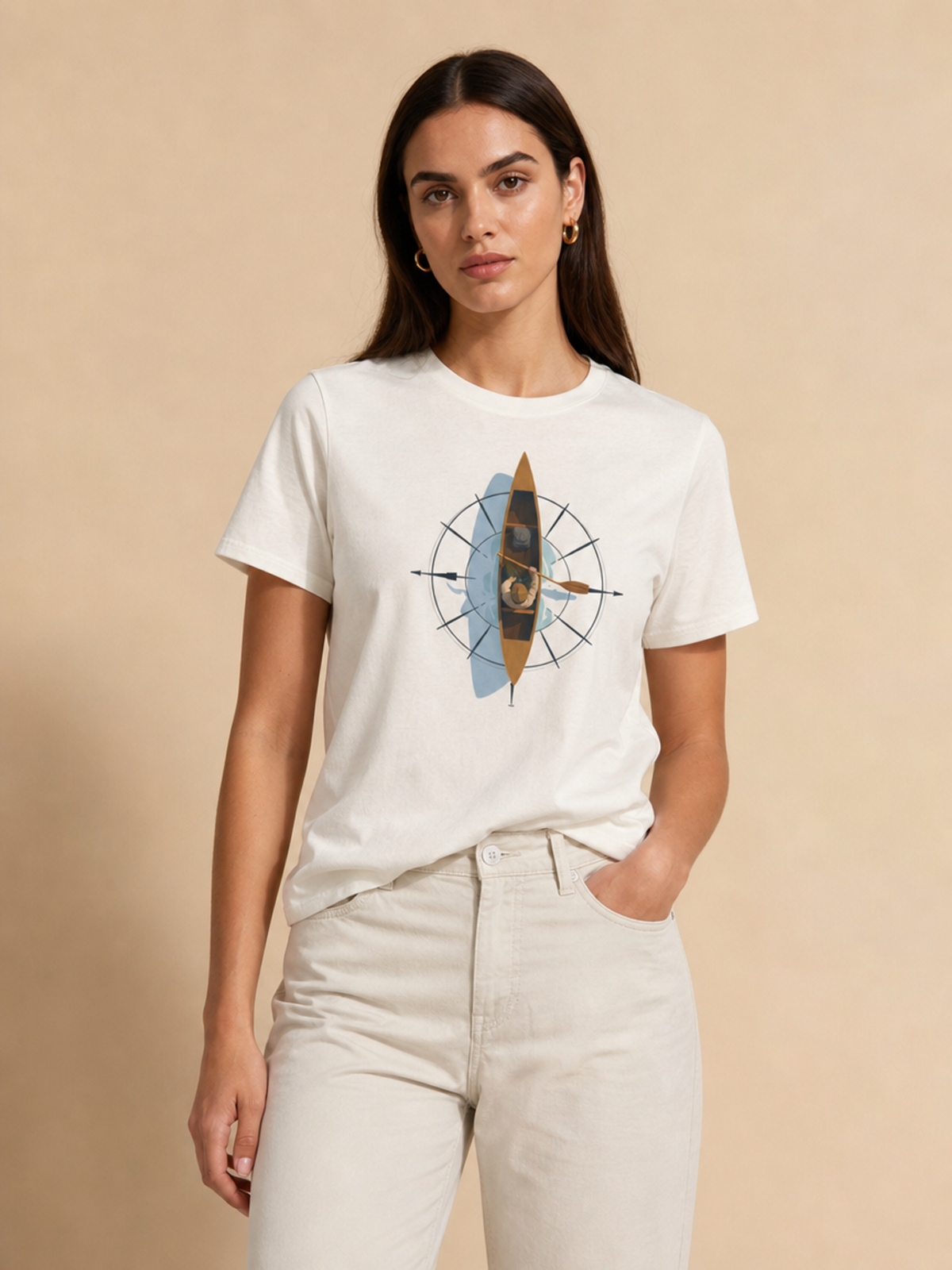 A woman modeling a white crewneck t-shirt with a central graphic of a stylized canoe inside a compass rose, paired with off-white jeans against a solid beige background.