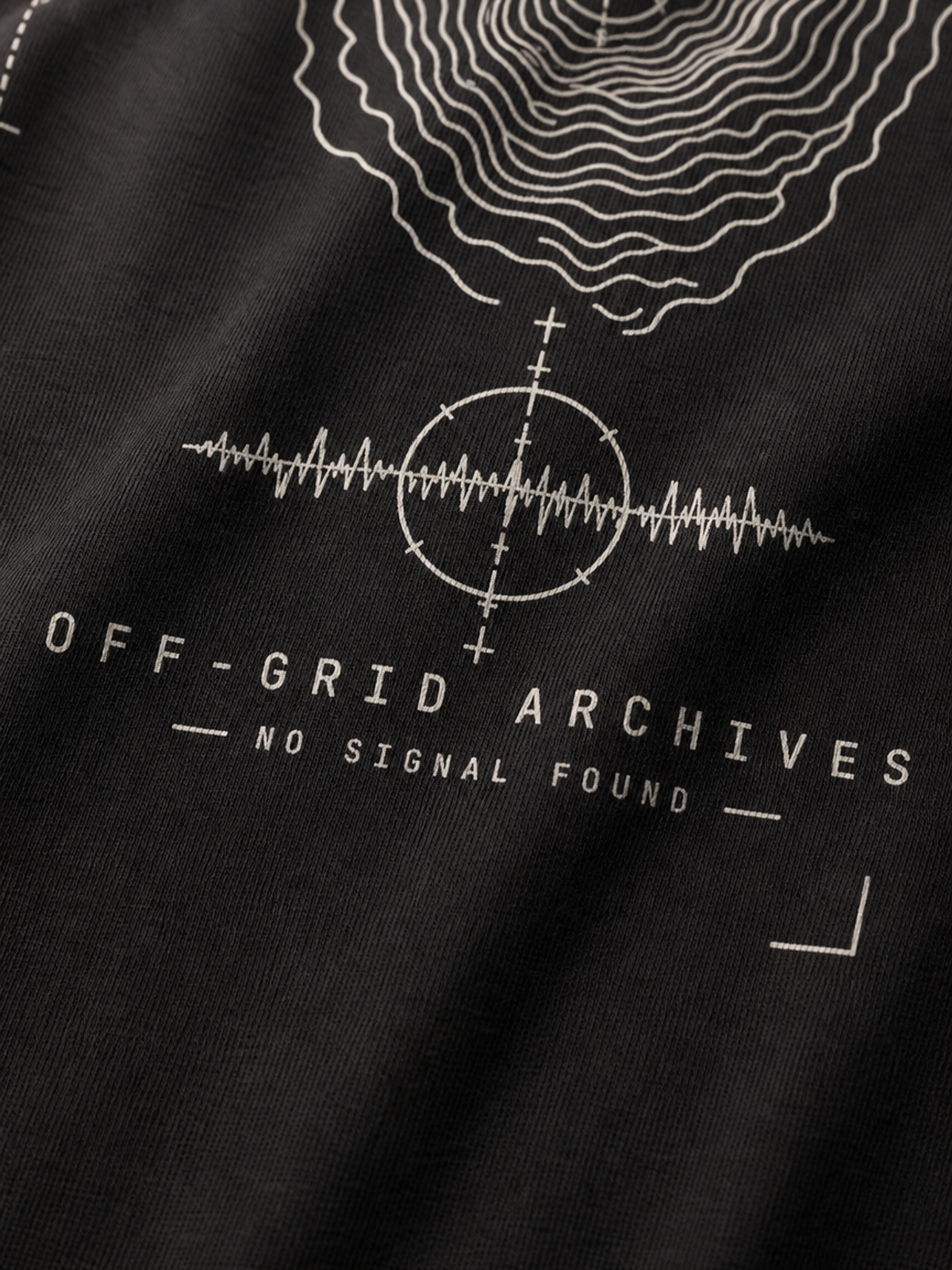 Close-up of a black fabric surface with a white graphic print featuring concentric contour lines, a signal waveform inside a circle, and the text 'OFF-GRID ARCHIVES' and 'NO SIGNAL FOUND'.