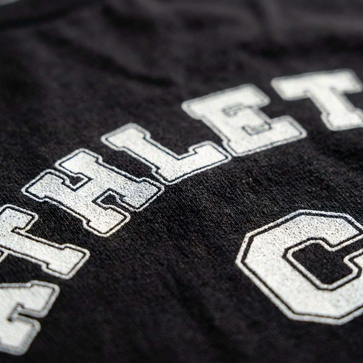 Front view of a black unisex eco-friendly t-shirt featuring a white vintage varsity-style 'Athletic C' graphic design.